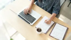 Persona al lavoro con computer portatile e documenti su una scrivania