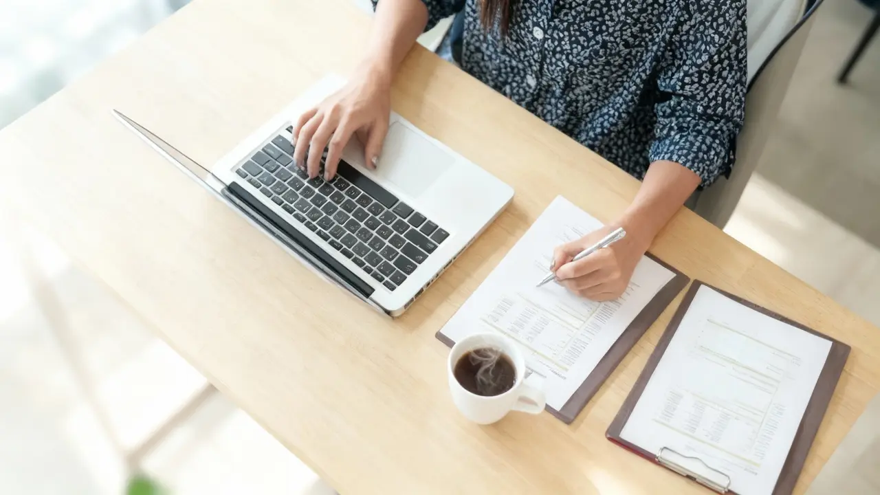 Persona al lavoro con computer portatile e documenti su una scrivania