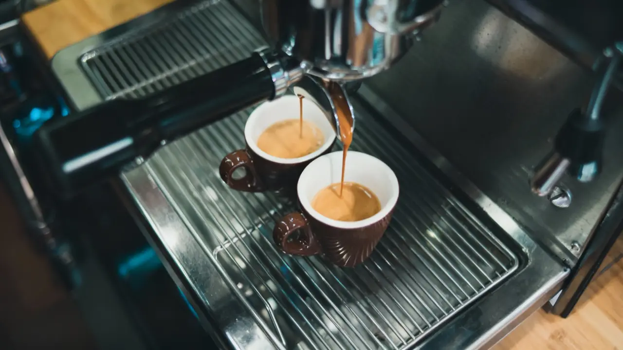 Due tazzine di caffè espresso scuro sotto una macchina da caffè