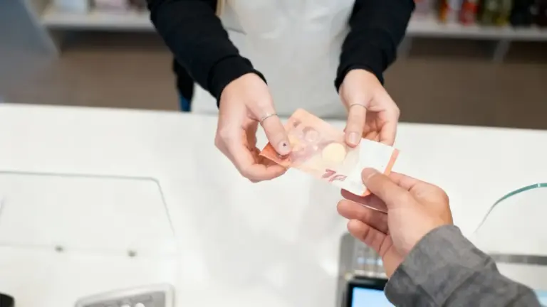 Una persona consegna una banconota da 10 euro a un'altra in un ambiente commerciale