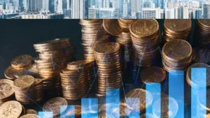 Pile di monete affiancate da grafici e skyline urbano sullo sfondo