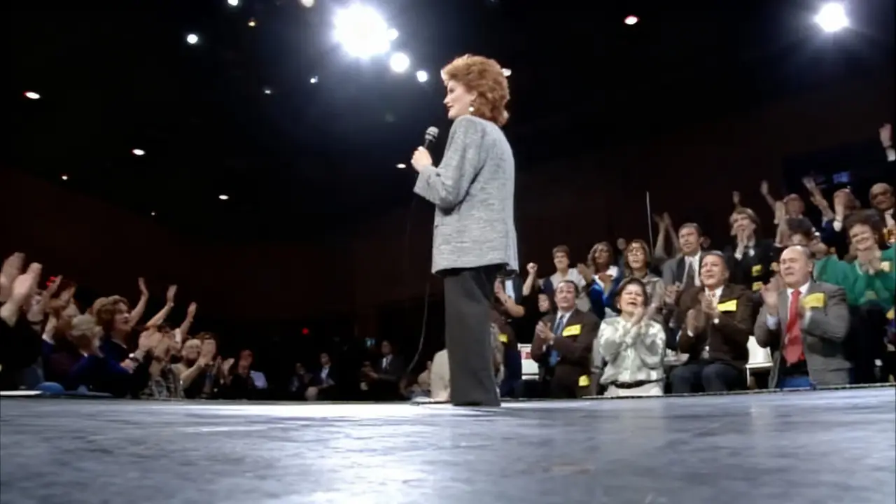 Una persona con microfono sul palco davanti a un pubblico applaudente in uno studio televisivo