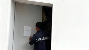 Un carabiniere affigge un avviso su una porta chiusa a Positano