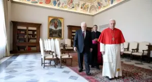 Tre uomini camminano in una sala elegante con decorazioni religiose e arredi classici