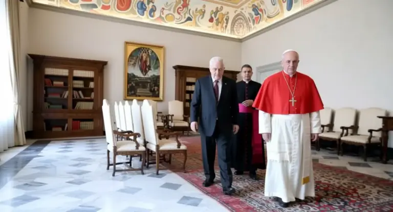 Tre uomini camminano in una sala elegante con decorazioni religiose e arredi classici