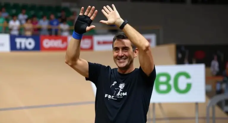 Una persona saluta con entrambe le mani alzate in un velodromo