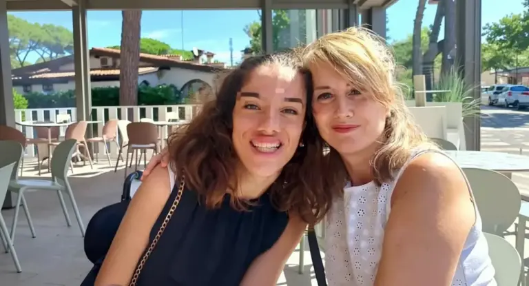 Due donne sedute insieme in un ambiente all'aperto, sorridenti e abbracciate