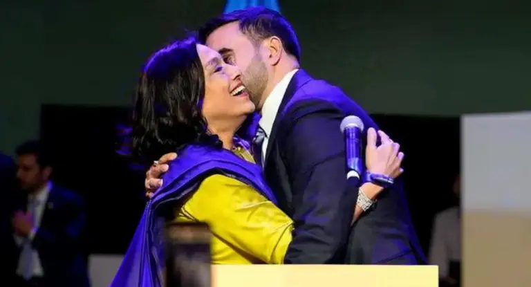 Una persona abbraccia un uomo in giacca davanti a un microfono su un palco