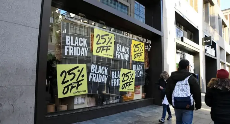 Vetrina di un negozio con cartelli di sconti per il Black Friday e persone che passano davanti