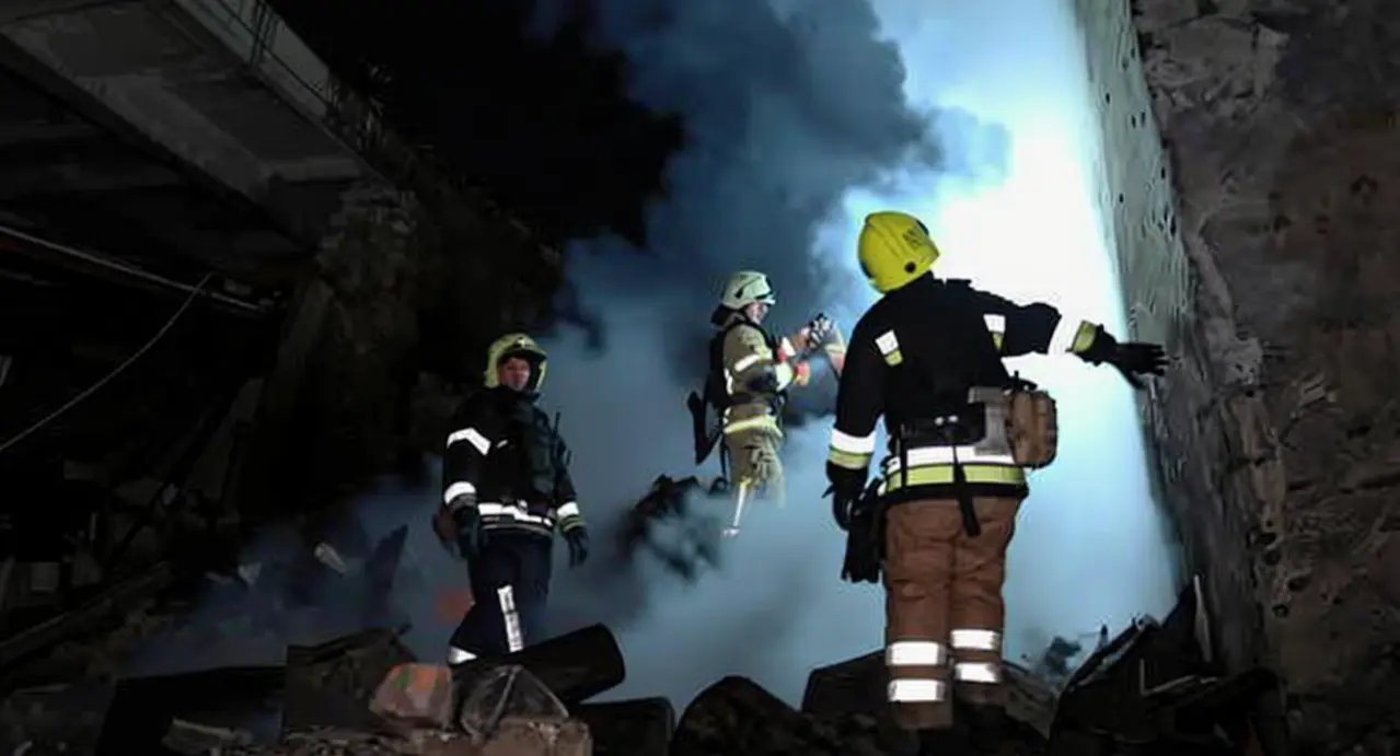 Vigili del fuoco tra le macerie di un edificio danneggiato da un raid notturno